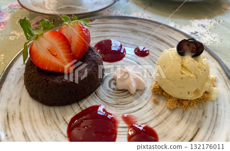 A delicious and beautifully plated gourmet dessert featuring a rich chocolate lava cake, or fondant, topped with fresh sliced strawberries 132176011