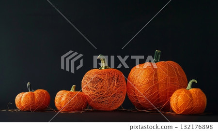 Five pumpkins wrapped in orange string sit on a black background. Halloween decor and craftwork, eco friendly, sustainable concept. 132176898
