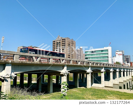 The cityscape of Okazaki City and Tonobashi Bridge shining against the clear blue autumn sky (Otogawa River Green Space, Okazaki City, Aichi Prefecture) 132177264