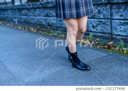 High school girls walking to and from school on a dark road for club activities on a cold day. High school girls' skirts are angled. 132177498