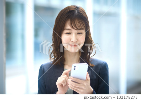 Business woman operating a smartphone Business woman operating a smartphone 132178275