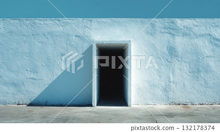 Minimalist Blue Wall With Dark Entrance Doorway and Sharp Shadow in Sunlit Exterior 132178374