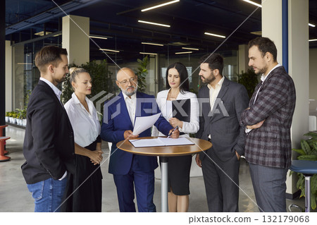 Executive leadership team reviewing documents during formal meeting in open office 132179068