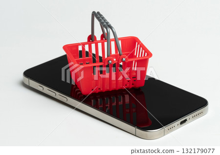 Red shopping basket sits atop mobile phone Red shopping basket sits atop mobile phone 132179077