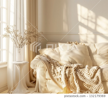A modern living room interior with a white couch, plush blanket, and decorative flowers in a vase 132179369
