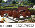 Workers are building solid brick walls of a house in a quiet suburban neighborhood. 132179532