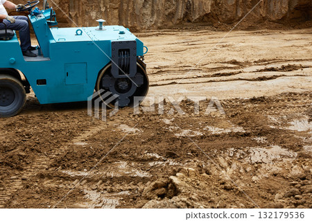 Blue roller compacts the ground on freshly dug soil at a construction site installed Blue roller compacts the ground on freshly dug soil at a construction site installed 132179536