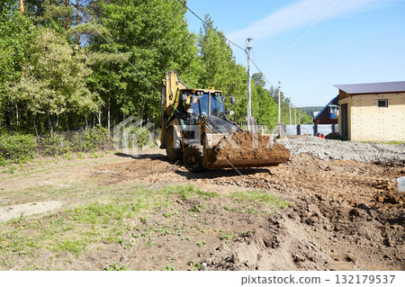 Heavy machinery moves dirt at a construction site with a clear focus on ground leveling and preparation for building 132179537