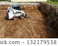 The excavator works to clear the soil and move it out of the excavation at the construction site 132179538
