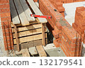 Workers are constructing a wall with clay bricks at a building site. 132179541