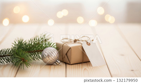 Rustic Christmas card template with a craft paper gift, blank tag, pine branch, and silver bauble on a wooden table. Rustic Christmas card template with a craft paper gift, blank tag, pine branch, and silver bauble on a wooden table. 132179950