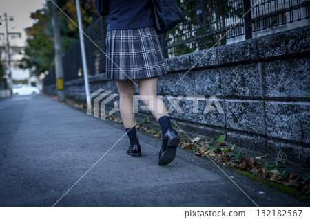 High school girl walking to and from school on a dark road for club activities on a cold day. High school student's skirt. Back view. Going to and from school. Negative image. High school girl walking to and from school on a dark road for club activities on a cold day. High school student's skirt. Back view. Going to and from school. Negative image. 132182567