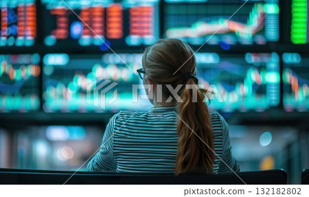 back view of professional female trader looking at monitor with stock exchange graph or chart, woman trading forex or cryptocurrency 132182802