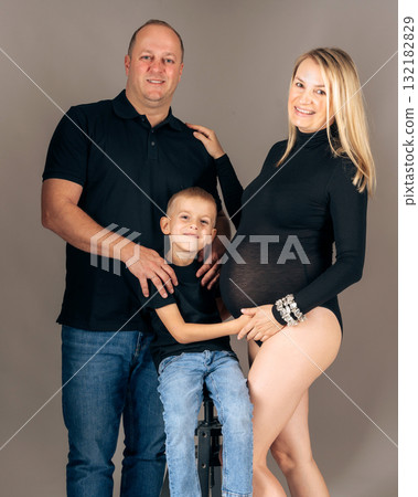 Family portrait with pregnant woman, husband, and child in casual black outfits loving parents and son posing together in studio Family portrait with pregnant woman, husband, and child in casual black outfits loving parents and son posing together in studio 132182829