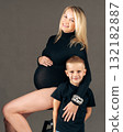 Pregnant woman sitting with young son hugging her family love and motherhood concept in studio 132182887