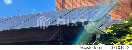Solar panels on a residential roof generating clean energy under a bright blue sky with sun flare 132183030