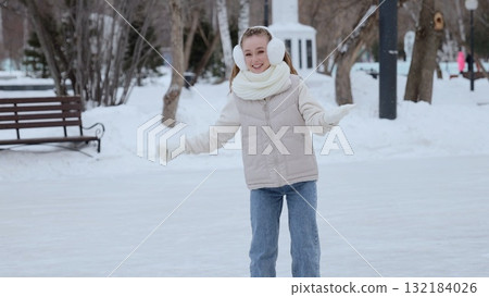 Teenage girl smiling, wearing winter accessories, gliding confidently across snowy park rink, enjoying cold weather skating moment with cheerful expression Teenage girl smiling, wearing winter accessories, gliding confidently across snowy park rink, enjoying cold weather skating moment with cheerful expression 132184026