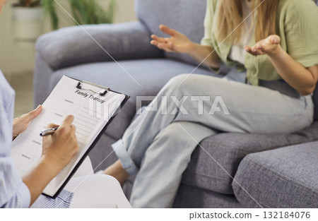 Therapist taking notes while patient gestures during supportive counseling session 132184076