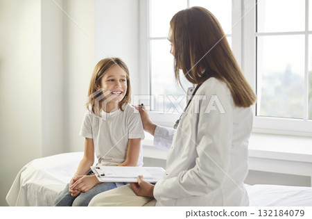 Female doctor talking with a child boy patient during medical examination in clinic. 132184079