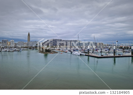 The marina and port of Le Havre with numerous boats and yachts moored, flanked by modern waterfront architecture, the Tour Saint-Joseph and the curved buildings of the Docks Vauban 132184905