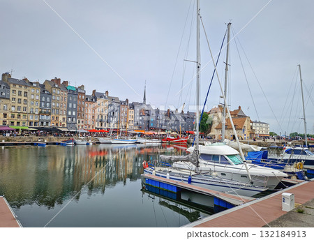 Honfleur, Normandy, France - May 30, 2025: Honfleur Vieux Bassin harbor with boats and yachts moored in the still water, and a row of colorful buildings in the background Honfleur, Normandy, France - May 30, 2025: Honfleur Vieux Bassin harbor with boats and yachts moored in the still water, and a row of colorful buildings in the background 132184913