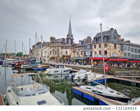 Honfleur, Normandy, France - May 30, 2025: Honfleur Vieux Bassin harbor with boats and yachts moored in the still water, and a row of colorful buildings in the background Honfleur, Normandy, France - May 30, 2025: Honfleur Vieux Bassin harbor with boats and yachts moored in the still water, and a row of colorful buildings in the background 132184914
