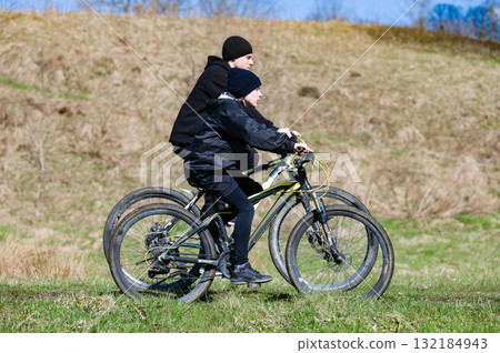 Two cyclists enjoy a ride through a grassy field on a sunny day. A beautiful outdoor adventure. 132184943