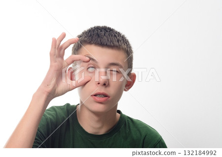 Teenager playfully covering one eye, quirky expression. 132184992