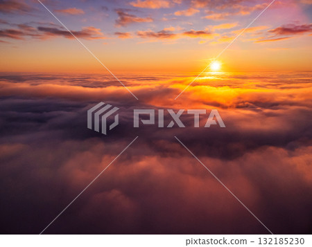 Dream-like photo of clouds of mist and a setting sun in the background. Flying with a drone above thick fog at sunset 132185230