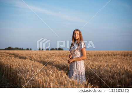 Young dreamy girl in field of ripe rye. Portrait of beautiful girl in field of wheat admiring the beauty of nature Young dreamy girl in field of ripe rye. Portrait of beautiful girl in field of wheat admiring the beauty of nature 132185270