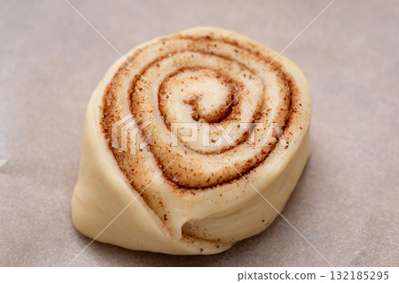 Raw cinnamon bun on baking paper. Cooking at home tasty buns with cinnamon powder 132185295