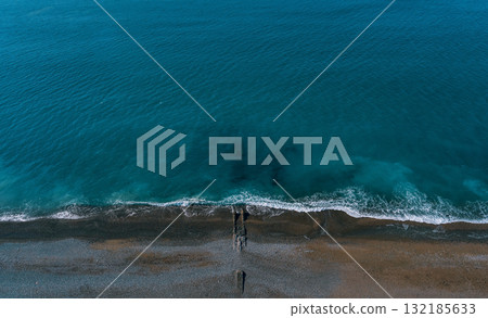 Aerial view of tranquil ocean waves gently lapping against a sandy beach shoreline Aerial view of tranquil ocean waves gently lapping against a sandy beach shoreline 132185633