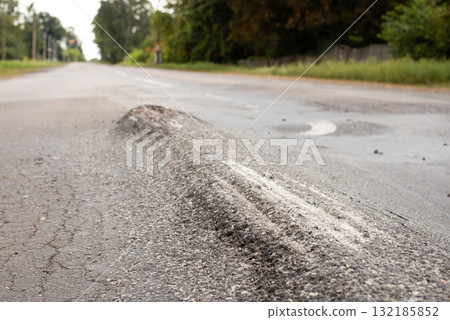 Road in terrible conditions with bumps on surface. Uneven road needs repairing Road in terrible conditions with bumps on surface. Uneven road needs repairing 132185852