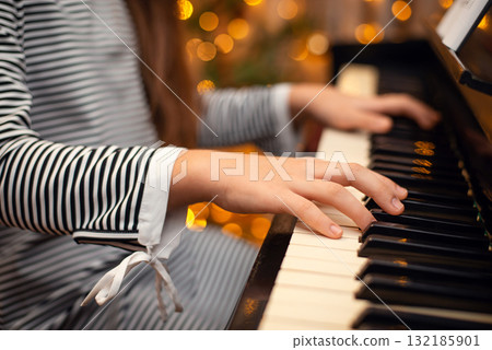 Girl's hands on the piano, close-up, beautiful bokeh in the background, woman playing the piano. Christmas lights and music, concert, family time, holidays concept. Girl's hands on the piano, close-up, beautiful bokeh in the background, woman playing the piano. Christmas lights and music, concert, family time, holidays concept. 132185901