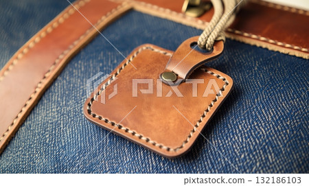 Close-up of a vintage leather luggage tag attached to a stylish travel bag. 132186103