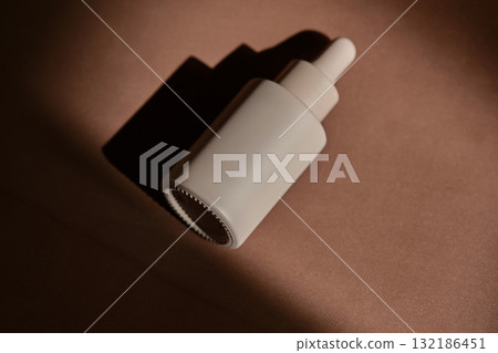 A bottle of face serum on a brown chocolate background. 132186451