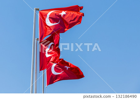 Turkish flags flutter atop tall flagpoles under a bright blue sky Turkish flags flutter atop tall flagpoles under a bright blue sky 132186490
