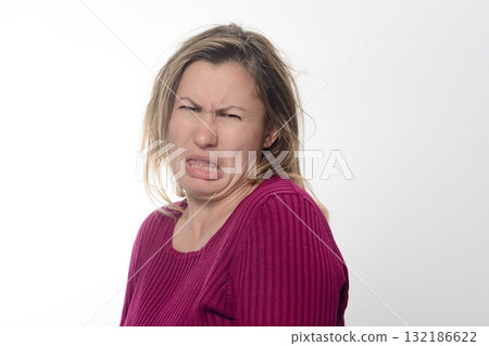 Woman making a disgusted face against white background. 132186622