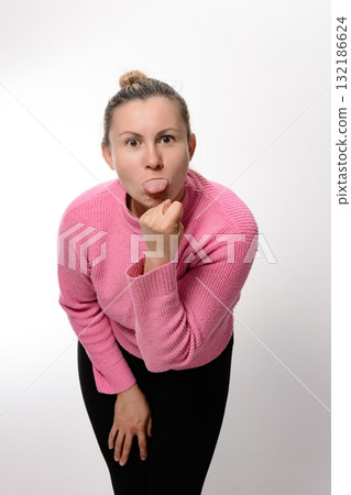Woman in pink sweater sticking out tongue and making a face. 132186624
