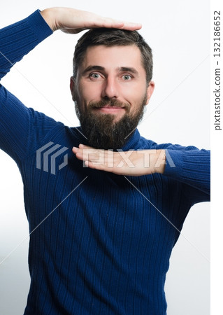 Bearded man framing his face with hands against a white background. 132186652