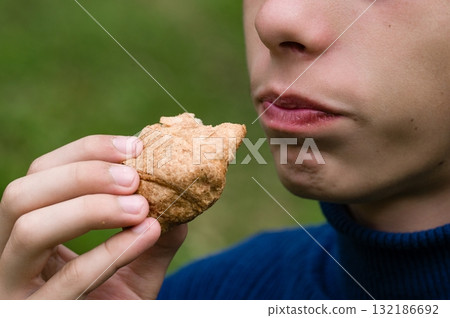 Person eating a pastry outdoors Person eating a pastry outdoors 132186692