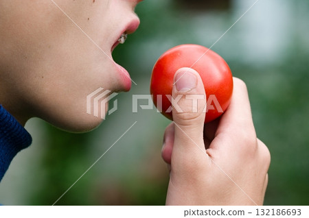 Person about to eat a ripe red fruit 132186693