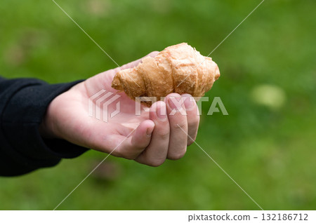 Hand holding a partially eaten pastry outdoors 132186712