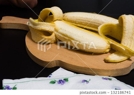 Peeled banana on wooden cutting board 132186741