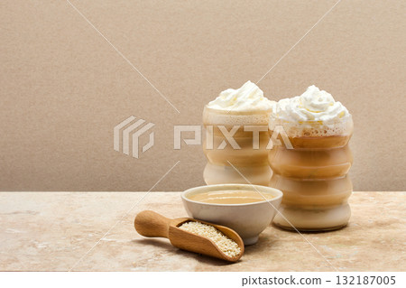 Creamy Tahini Latte Coffee and with tahini cream bowl and sesame seeds on a marble travertine Creamy Tahini Latte Coffee and with tahini cream bowl and sesame seeds on a marble travertine 132187005