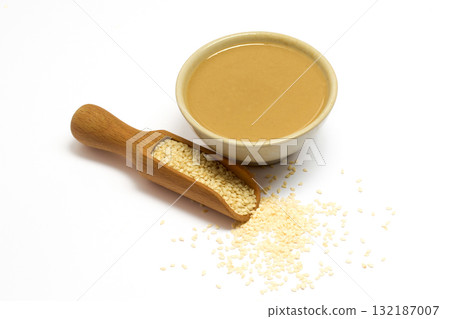 Sesame Seeds and Tahini. A bowl of creamy tahini next to a scoop of sesame seeds 132187007