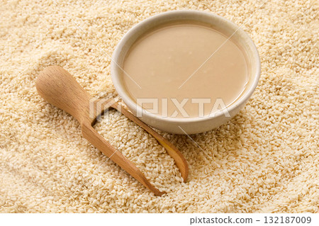 Tahini and Sesame Seeds. A bowl of tahini surrounded by sesame seeds Tahini and Sesame Seeds. A bowl of tahini surrounded by sesame seeds 132187009