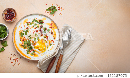 Turkish eggs cilbir, Middle Eastern style breakfast on beige background table top view, space for text 132187073