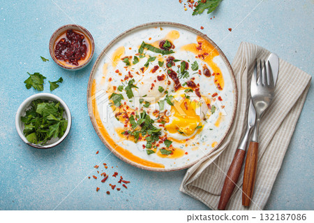 Turkish eggs cilbir, Middle Eastern style breakfast on blue background table top view 132187086