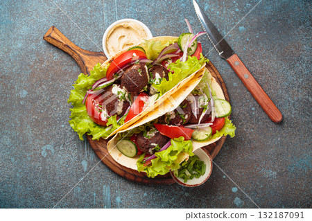 Falafel tacos with fresh vegetables and creamy tahini sauce served with hummus 132187091